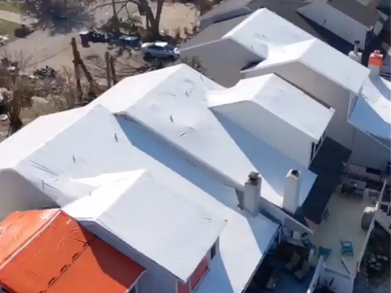 A drone picture of already tarped roof of a house.
